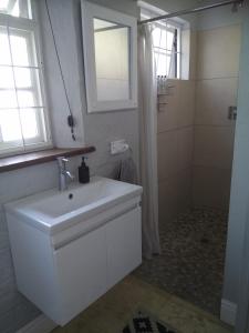 y baño blanco con lavabo y ducha. en Pelican Cottage - 800m from Beach & Yacht School en Hout Bay