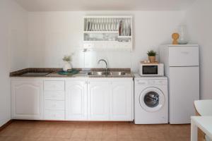 een keuken met witte kasten en een wasmachine en droger bij Sweet Caleta in Caleta de Caballo