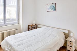 a white bed in a white bedroom with a window at À 600m de la plage, maison pour 6 avec terrasse in Le Guilvinec