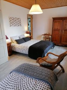 1 dormitorio con 2 camas y 1 silla en Maison La Vigne - Gîtes et Chambres d'hôtes, en Le Chambon-sur-Lignon