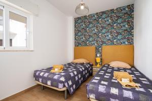 una camera con due letti e una parete con carta da parati di Apartamentos Old Town by Umbral ad Albufeira