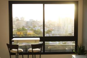 two chairs in front of a window with a view of a city at Ap no coração de POA in Porto Alegre