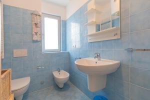 een blauw betegelde badkamer met een wastafel en een toilet bij Appartamento Barbarossa by HelloElba in Porto Azzurro