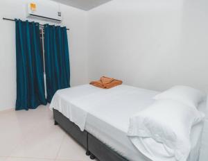 1 cama blanca con cortinas azules en una habitación en Casa Guaviare, La Mejor Opción Para Ti, en San José del Guaviare