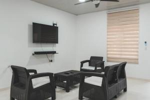 サン・ホセ・デル・グアビアレにあるCasa Guaviare, La Mejor Opción Para Tiの椅子、テーブル、薄型テレビが備わる客室です。
