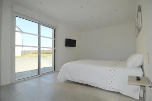 biała sypialnia z łóżkiem i dużym oknem w obiekcie Saint Côme Beach House w mieście Saint-Côme-de-Fresné +4 zdjęcia