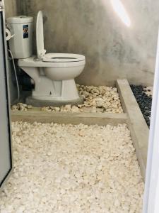 a bathroom with a toilet in a room filled with rocks at Lapwing Lake Villa in Tissamaharama