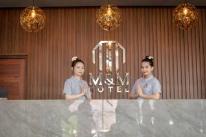 two girls standing behind a marble counter in a room at M&M Hotel in Vang Vieng