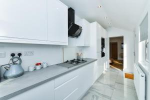 cocina con armarios blancos y fogones en Claude House - charming 4Bedroom Home, en Nottingham