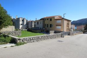 a stone retaining wall in front of some buildings at Apartment Smokvina P in Baška
