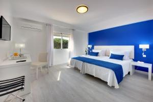 a bedroom with a large bed with a blue wall at Zodiaco in Quarteira