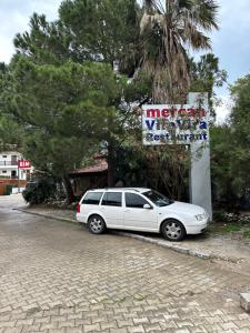 un coche blanco estacionado frente a una gasolinera en MANDALİN AKYAKA, en Akyaka