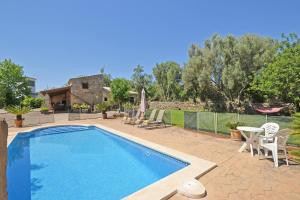 a swimming pool with chairs and a house at Villa Alba in Llubí