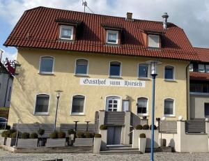 a large yellow building with a red roof at Pension Hirsch in Berg