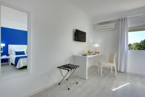 a white bedroom with a bed and a desk and a chair at Zodiaco in Quarteira