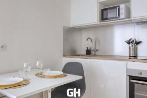 a kitchen with a table with two plates and glasses at Le Season - Bel appartement - Proche Disney & Paris RER E in Villiers-sur-Marne