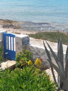 a sign for a beach with flowers and the ocean at Glaros Rooms in Koufonisia