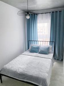 una camera da letto con un letto con tende blu e una finestra di IgoAparts Wroblewskiego a Łódź