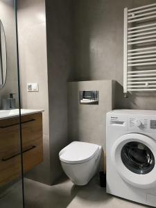a bathroom with a toilet and a washing machine at IgoAparts Wroblewskiego in Łódź