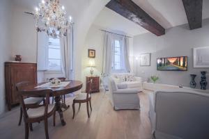 ein Wohnzimmer mit einem Tisch, Stühlen und einem Kronleuchter in der Unterkunft Apartments Florence Parione in Florenz