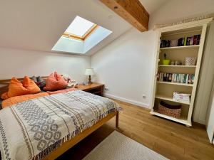 1 dormitorio con cama con almohadas de color naranja y tragaluz en Appartment Via Claudia, en Schongau
