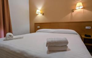 a hotel room with a bed with two towels on it at Hotel Santa Faz in San Juan de Alicante