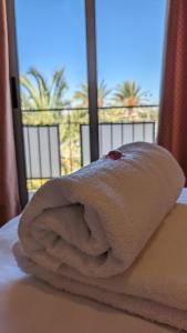 a towel sitting on top of a bed with a window at Hotel Santa Faz in San Juan de Alicante