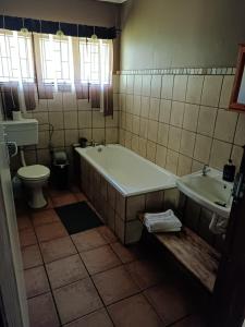a bathroom with a tub and a toilet and a sink at Little Rock Resort in Ladybrand +29 photos
