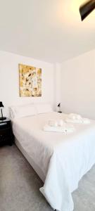 a white bed with white sheets and towels on it at Atico a dos minutos de la playa in Fuengirola