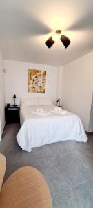 a bedroom with a white bed with a ceiling fan at Atico a dos minutos de la playa in Fuengirola