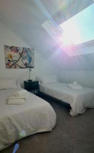 two beds in a room with the sun shining through a window at Atico a dos minutos de la playa in Fuengirola