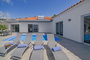 a swimming pool with lounge chairs next to a house at Villa Calhetascape by Villa Plus in Estreito da Calheta