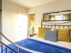 a bedroom with a bed with blue sheets and yellow pillows at Tudors eSuites 4 Bedroom House Driveway & Garden in Birmingham
