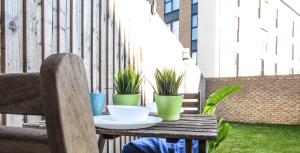 a wooden table with bowls and potted plants on a patio at Tudors eSuites 4 Bedroom House Driveway & Garden in Birmingham