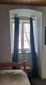a bedroom with a bed and a window with blue curtains at Turmhaus Trieben Wohnung 1 in Trieben