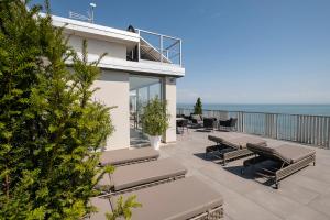 un patio con bancos, mesas y el océano en DIVA HOTEL LIGNANO - Adults Only en Lignano Sabbiadoro
