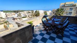 a table and chairs on a balcony with a view of a city at Qala Bed&Breakfast with swimming pool - IL-Wenniessa in Qala