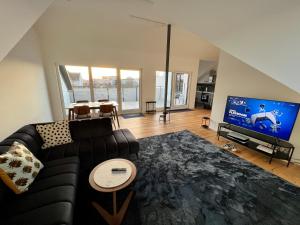 ein Wohnzimmer mit einem Sofa und einem Flachbild-TV in der Unterkunft Apartment Lili-PS5-Terrace-View-Bright-Kitchen-2xBedroom in Offenbach