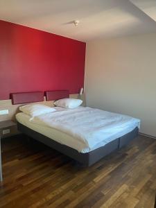 a bed in a room with a red wall at Swiss Star Irchel - Self Check-In in Zurich