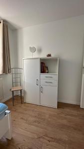 ルブミンにあるFerienwohnung "Am Walde"の白いキャビネットと椅子が備わる客室です。
