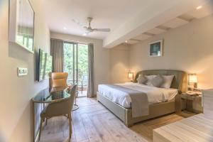 a bedroom with a bed and a desk with a chair at The Fern Residency Calangute-Baga, Goa in Calangute