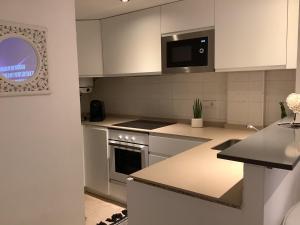 a kitchen with white cabinets and a microwave at Apartamento Playa Denbossa in Playa d'en Bossa