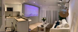 a kitchen and a living room with a large screen at Apartamento Playa Denbossa in Playa d'en Bossa