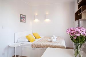 um quarto branco com um sofá com almofadas e flores em Marine Studio by Tyzenhauz em Gdansk
