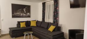 Ferienwohnungen Vörstetten في Vörstetten: غرفة معيشة مع أريكة سوداء ووسائد صفراء