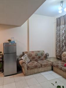 ein Wohnzimmer mit einem Sofa und einem Kühlschrank in der Unterkunft Almond Tower, Garden City in Ajman 