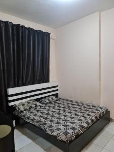 a bed in a room with a black curtain at Almond Tower, Garden City in Ajman 