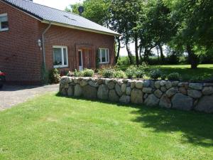 ein Backsteinhaus mit einer Steinmauer vor einem Hof in der Unterkunft Ferienhof Nickelswarft Fewo 2 in Poppenbüll