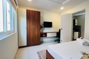 a bedroom with a bed and a desk with a television at BluO 1BHK Suite Gachibowli - Terrace Garden, Lift in Hyderabad