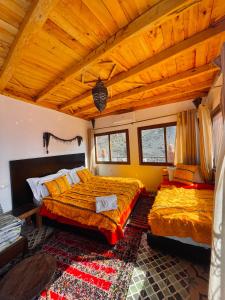 een slaapkamer met 2 bedden en een houten plafond bij Kasbah Imlil in Imlil